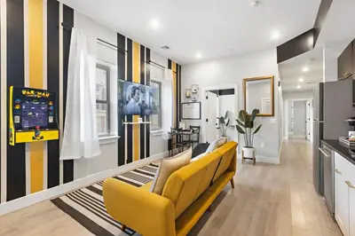 a living room with yellow chairs and a video game at 4BR Duplex, Prime Location in Newark