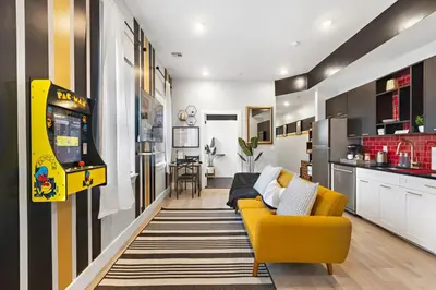 a living room with a yellow couch and a video game at 4BR Duplex, Prime Location in Newark