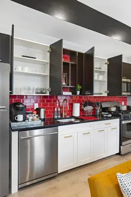 a kitchen with stainless steel appliances and red tiles at 4 Suites Near Downtown Newark in Newark