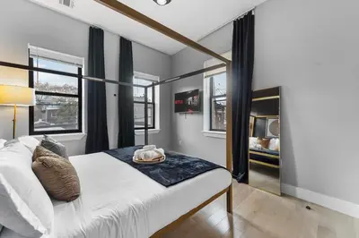 a bedroom with a large white bed with windows at 4 Suites Near Downtown Newark in Newark
