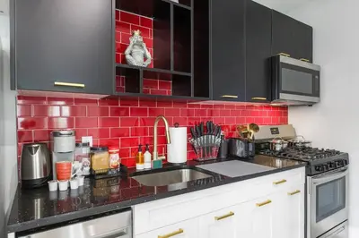 a kitchen with a sink and a red tile wall at 4 Suites Near Downtown Newark in Newark