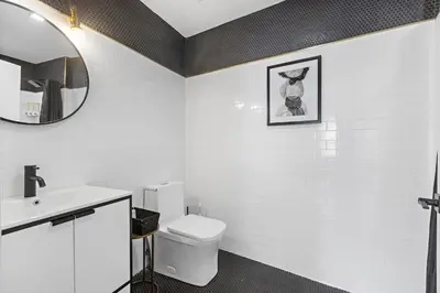 a white bathroom with a toilet and a mirror at 4 Suites Near Downtown Newark in Newark