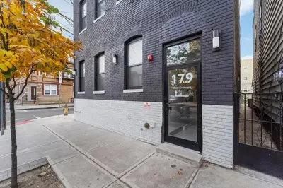 a black brick building with a door on a street at 4 Suites Near Downtown Newark in Newark
