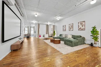 a living room with a green couch and a large white wall at Soho Fancy 4 Bedroom 2000 square feet Loft in New York