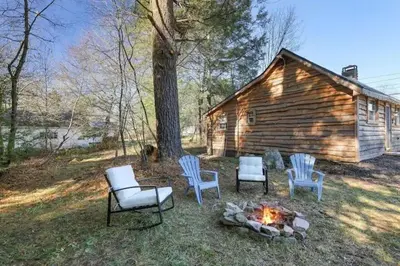 a group of chairs and a fire pit in front of a cabin at The Cozy Cabin in Blakeslee