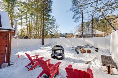 a patio with red chairs and a lantern in the snow at The Rustic Cabin in Blakeslee