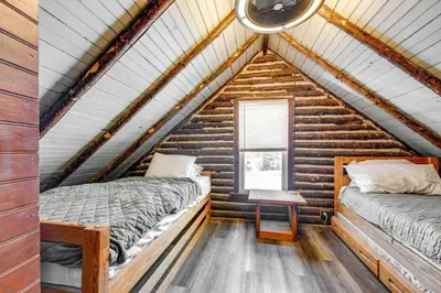 two beds in a log cabin bedroom with a window at The Rustic Cabin in Blakeslee