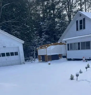 a house and a garage with snow on the ground at The Babbling Brooke in Blakeslee