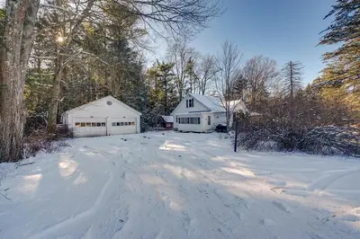 a snow covered yard with two white buildings and trees at The Babbling Brooke in Blakeslee