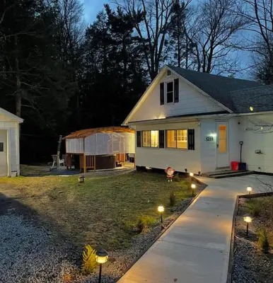 a white house with lights in the yard at The Babbling Brooke in Blakeslee