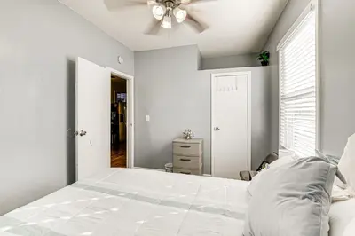 a white bedroom with a bed and a ceiling fan at 1 Mi to Downtown Newark Urban Escape! in Newark