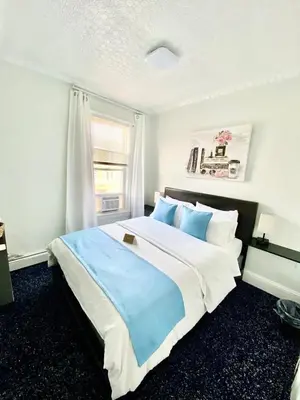 a bedroom with a large bed with blue sheets and a window at Entire House in West Ny, NJ12 mints from NYCity Time Square in West New York