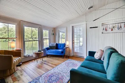 a living room with a blue couch and windows at Heart's Desire, a Cottage With Stunning Lake Views in Effort