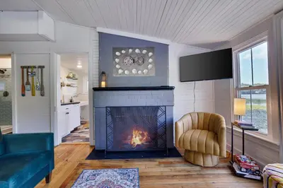a living room with a fireplace and a chair at Heart's Desire, a Cottage With Stunning Lake Views in Effort
