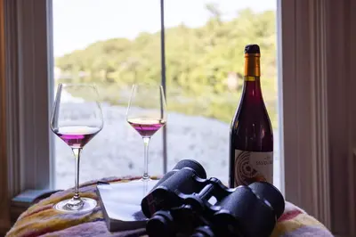 a bottle of wine and two glasses on a table at Heart's Desire, a Cottage With Stunning Lake Views in Effort