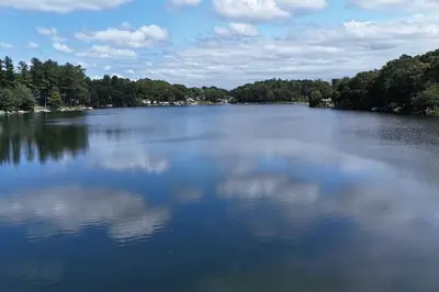a large lake with trees and clouds in the water at Heart's Desire, a Cottage With Stunning Lake Views in Effort