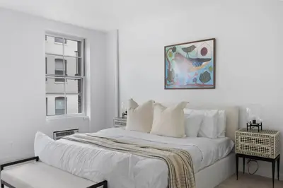 a white bedroom with a bed and a window at Chelsea Canvas III by Rove Travel Charming 2BR Gem in New York