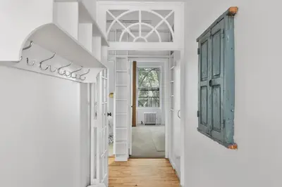 a hallway with white walls and a blue cabinet at Chelsea Canvas III by Rove Travel Charming 2BR Gem in New York