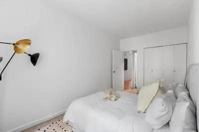 a white bedroom with a white bed and a lamp at Chelsea Canvas III by Rove Travel Charming 2BR Gem in New York