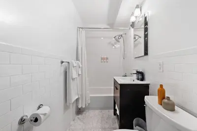 a white bathroom with a shower and a sink at Chelsea Vista II by Rove Travel 2BR PH with Rooftop in New York