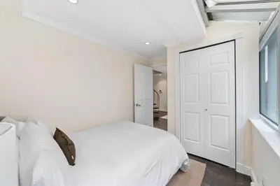 a white bedroom with a white bed and a window at Chelsea Vista II by Rove Travel 2BR PH with Rooftop in New York