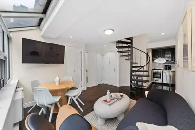 a living room with a staircase and a table and chairs at Chelsea Vista II by Rove Travel 2BR PH with Rooftop in New York