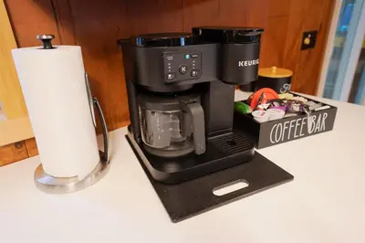 a coffee maker on a counter next to a roll of paper towels at Arrowheadlake,videogames,fireplace,firepit,grill in Thornhurst