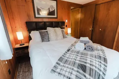 a bedroom with a large white bed with wooden walls at Arrowheadlake,videogames,fireplace,firepit,grill in Thornhurst