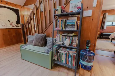 a book shelf with a couch and a bottle of water at Arrowheadlake,videogames,fireplace,firepit,grill in Thornhurst