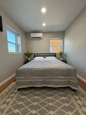 a bedroom with a large bed and two windows at Cozy Cottage Flexible Stay in Wrightsville