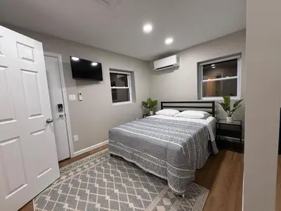 a bedroom with a bed and a flat screen tv at Cozy Cottage Flexible Stay in Wrightsville