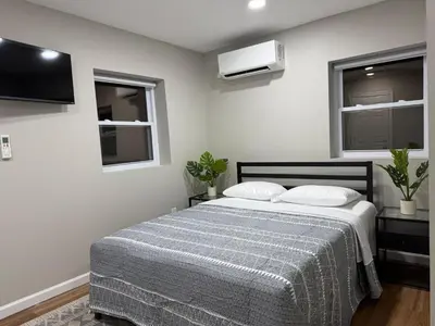 a bedroom with a bed with two pillows and a tv at Cozy Cottage Flexible Stay in Wrightsville