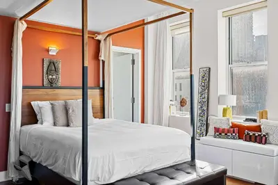 a bedroom with a canopy bed with an orange wall at Broadway Terrace by Rove Loft with Private Terrace in New York