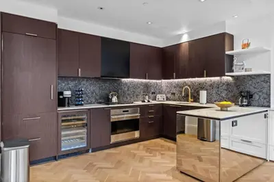 a kitchen with brown cabinets and a wooden floor at Clinton by Rove Travel 3BR Duplex with Backyard in New York