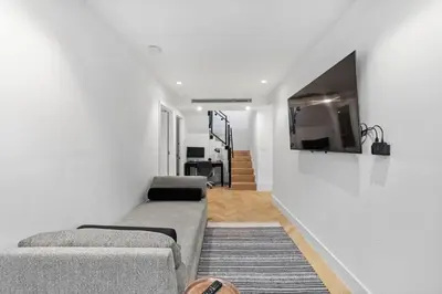 a living room with a couch and a tv on a wall at Clinton by Rove Travel 3BR Duplex with Backyard in New York