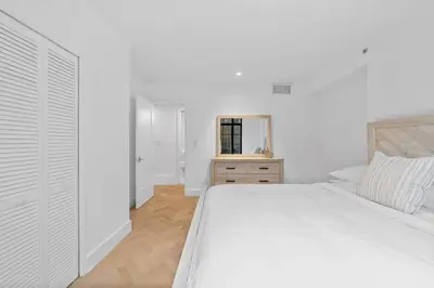a white bedroom with a white bed and a mirror at Clinton by Rove Travel 3BR Duplex with Backyard in New York