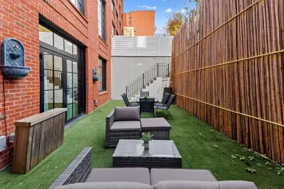 a patio with couches and a table on the grass at Clinton by Rove Travel 3BR Duplex with Backyard in New York