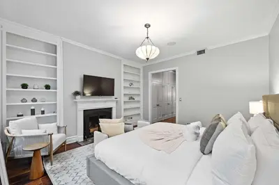a white bedroom with a bed and a fireplace at Downing by Rove Travel Private Terrace & Patio in New York