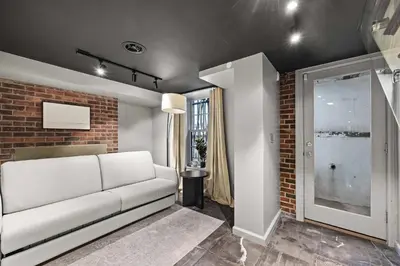 a living room with a white couch and a brick wall at Downing by Rove Travel Private Terrace & Patio in New York