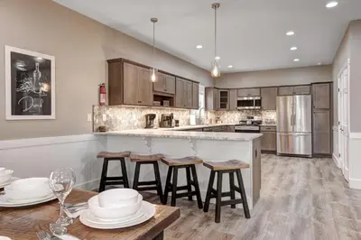 a kitchen with wooden cabinets and a bar with stools at New Luxury Lakeview Haven with Lake Access, HotTub, Game Room, Sleeps 26 in Lake Harmony