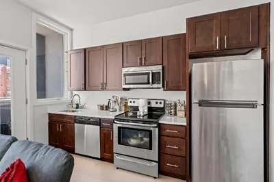 a kitchen with wooden cabinets and a stainless steel refrigerator at Modern 1BR Apartment Downtown Philly Near MET in Philadelphia