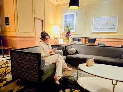 a woman sitting on a couch looking at her cell phone at Executive Hotel Le Soleil New York in New York