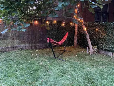 a chair sitting in the grass under a tree with lights at Brand New Modern Flat, Heart of University City in Philadelphia