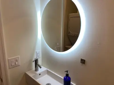 a bathroom with a round mirror above a sink at Brand New Modern Flat, Heart of University City in Philadelphia