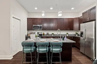a kitchen with wooden cabinets and a large island with bar stools at Luxury 3BR Rooftop Apartment Walk to MET and Metro in Philadelphia