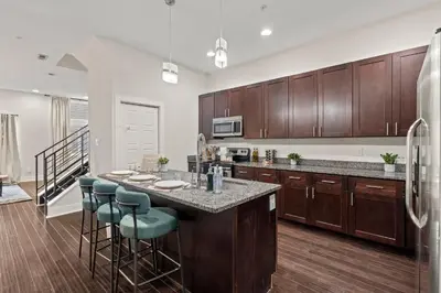 a kitchen with wooden cabinets and a kitchen island with bar stools at Luxury 3BR Rooftop Apartment Walk to MET and Metro in Philadelphia