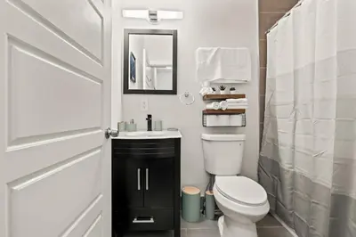 a bathroom with a toilet and a sink and a mirror at Luxury 3BR Rooftop Apartment Walk to MET and Metro in Philadelphia