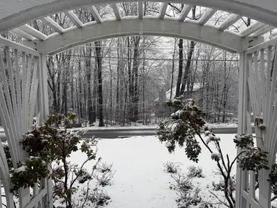 an arched entry to a garden in the snow at Hillsaps Ranch on the Lake in Gouldsboro
