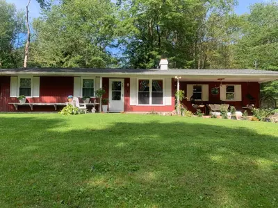 a red house with a green lawn in front of it at Hillsaps Ranch on the Lake in Gouldsboro