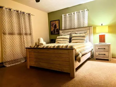 a bedroom with a bed and a lamp and curtains at The CubHouse Poconos getaway in Tobyhanna